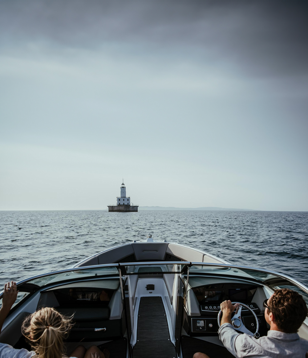 Pärchen fährt mit ihrem Motorboot auf einen Leuchtturm zu